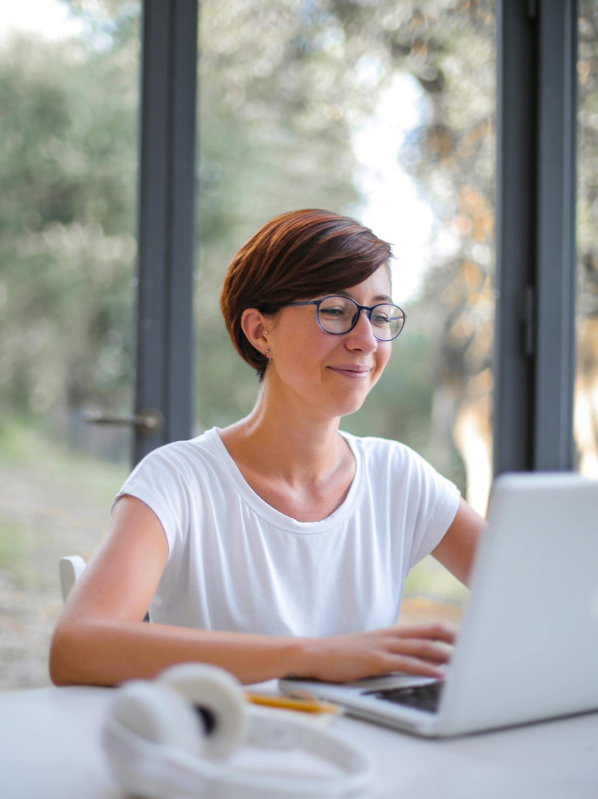 A happy woman with short hair using a laptop indoors, showcasing remote work lifestyle.